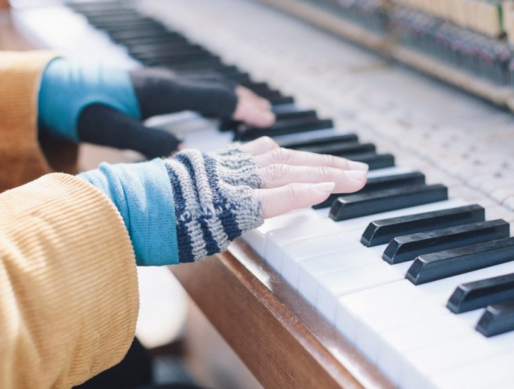 hands in gloves playing piano outside