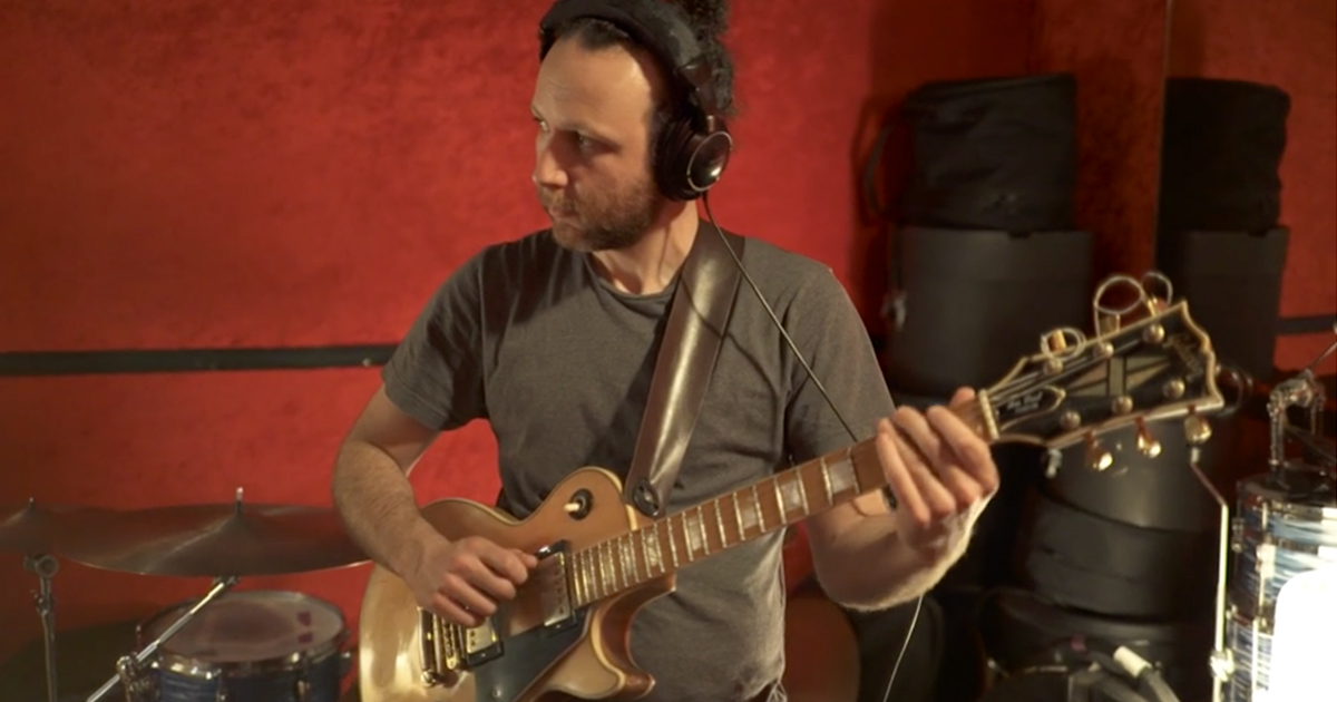man recording guitar in a studio