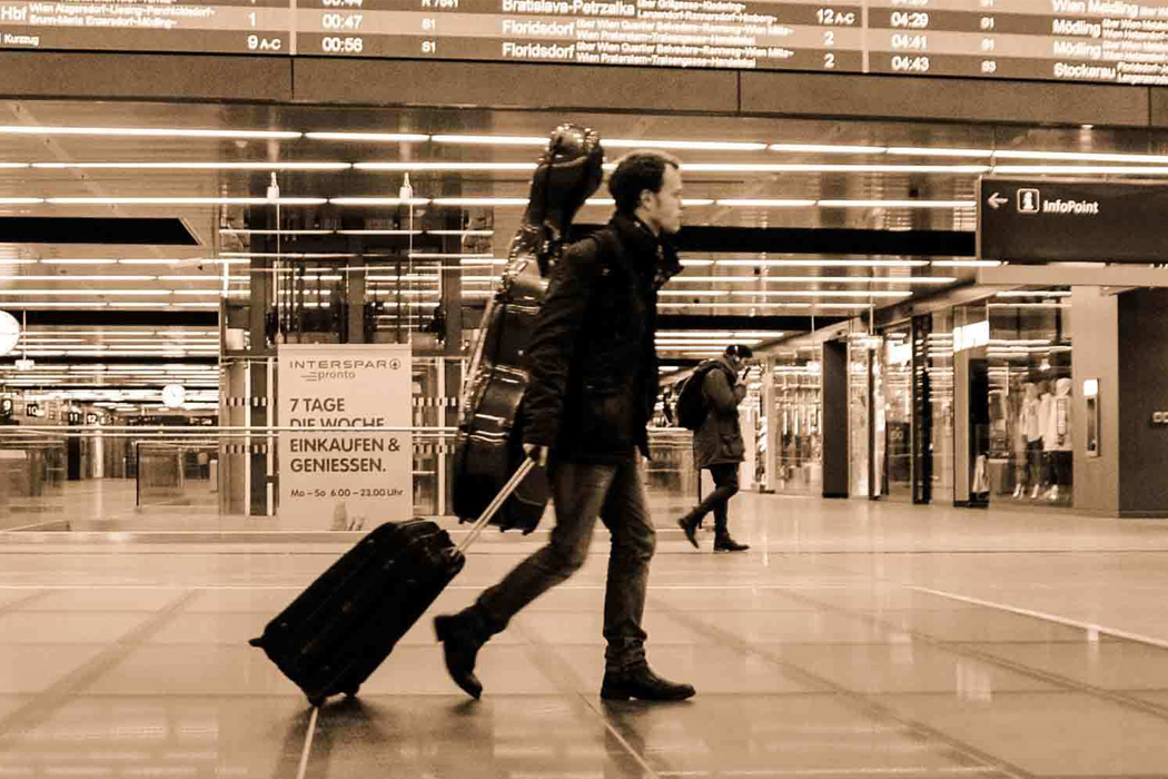 man with cello in travel case walking in airport