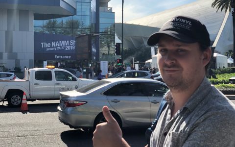 Carter Lee posing in front of NAMM sign