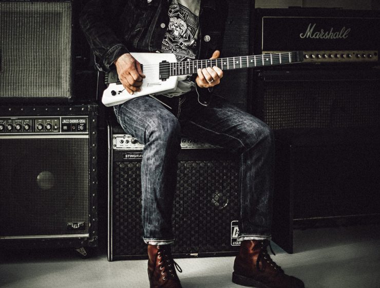 male guitarist sitting on amps playing