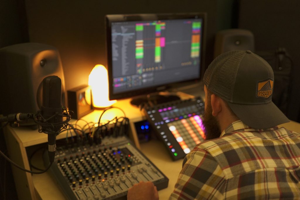 man producing music in lamplit home studio