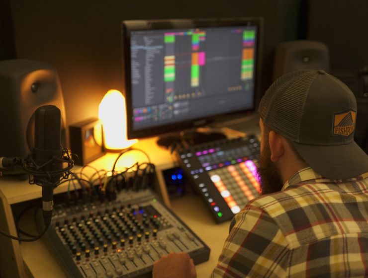 man producing music in lamplit home studio