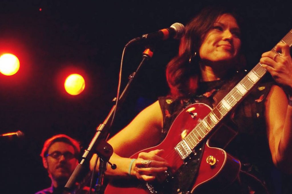 Ellisa Sun playing guitar with her band on stage