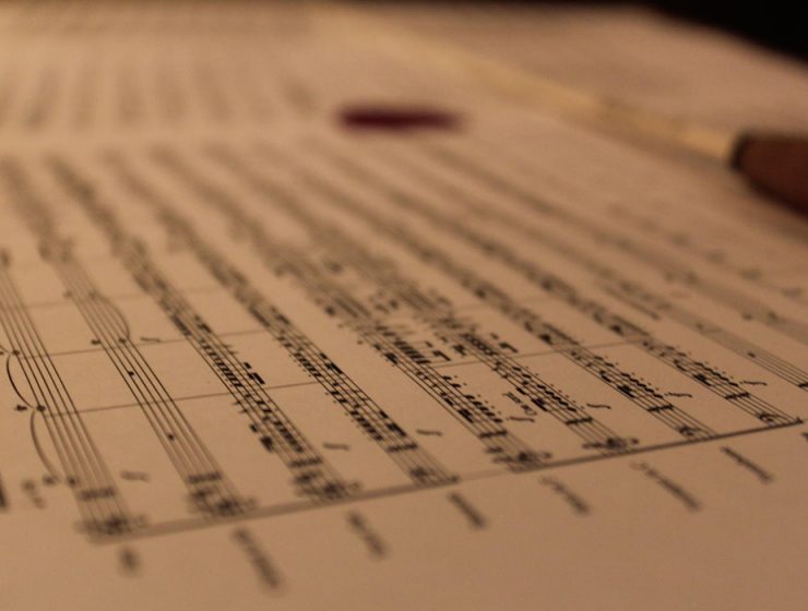 closeup of sheet music with conductor baton