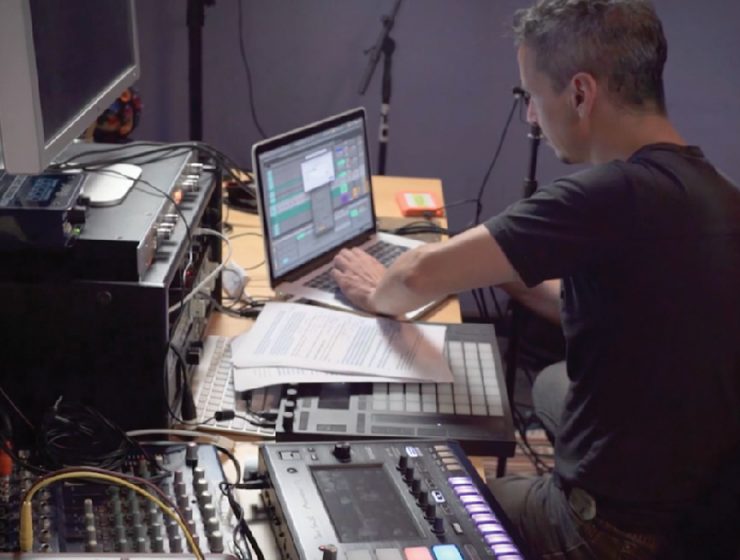 man in messy studio working on music on the computer