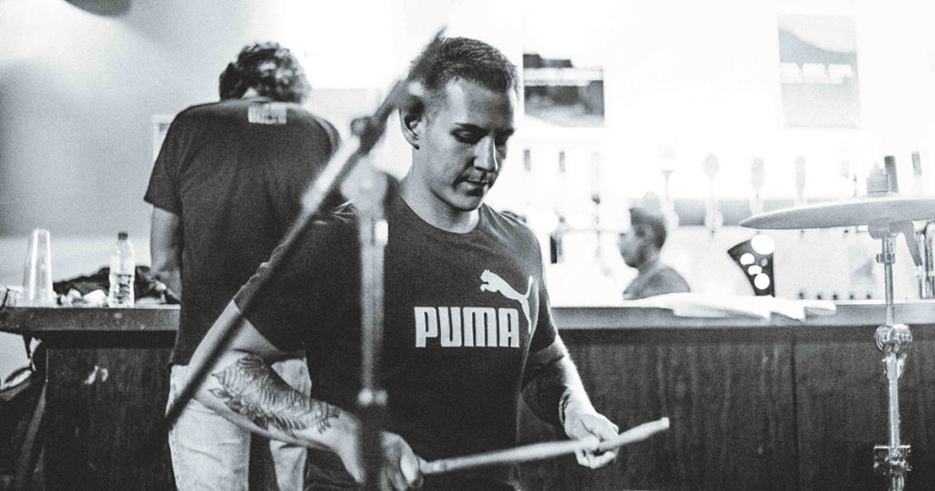 man practicing drums backstage at a concert