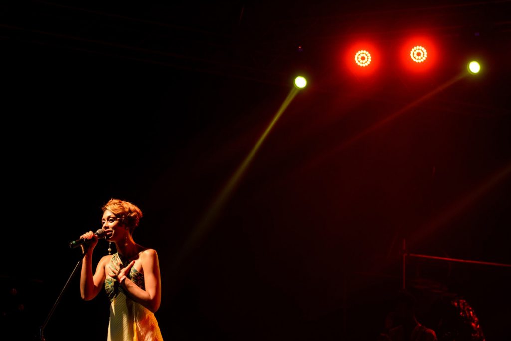 woman singing on a big stage under lights