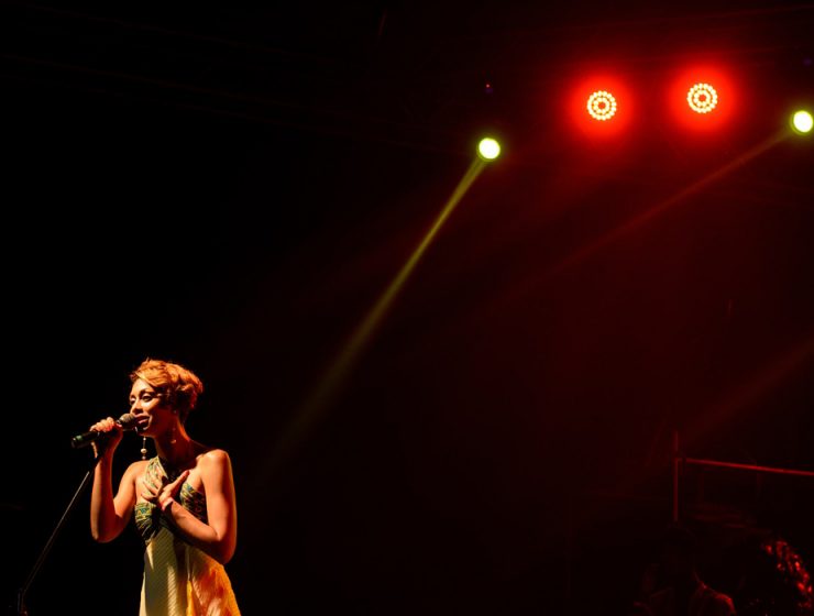 woman singing on a big stage under lights