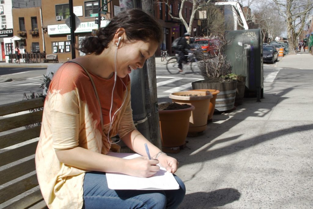 girl writing lyrics on the street