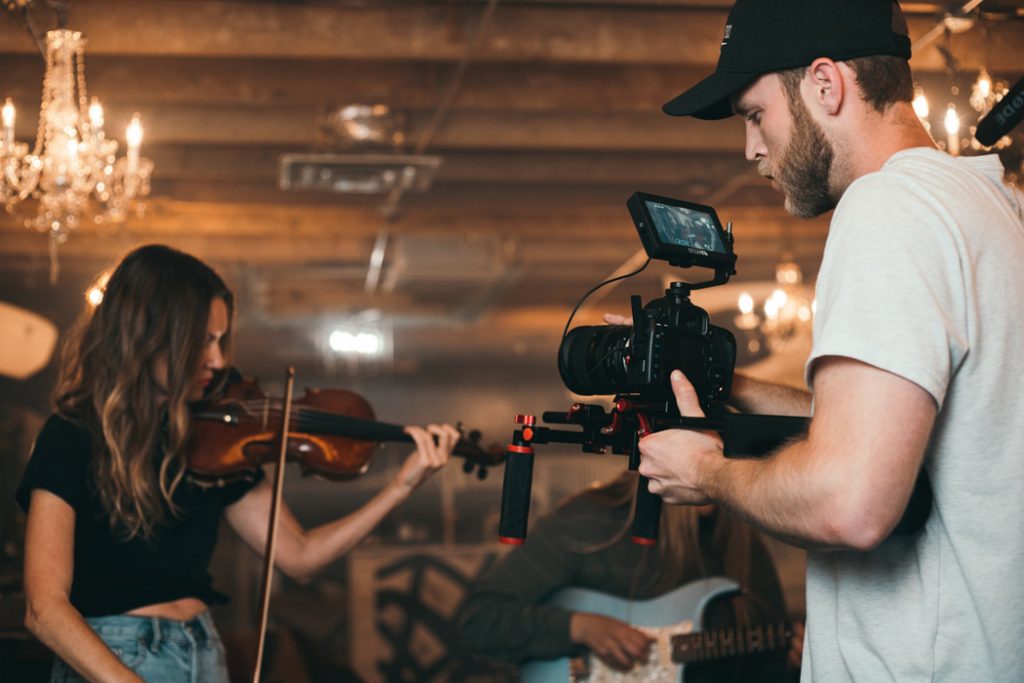 Man filming woman playing violin