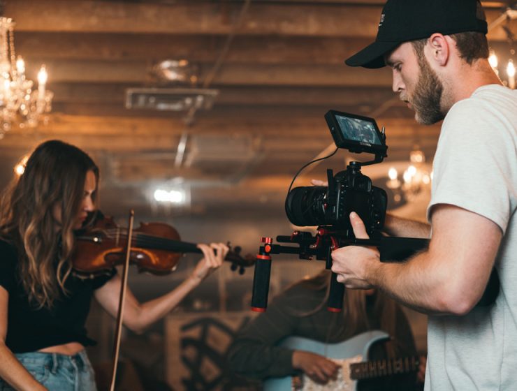 Man filming woman playing violin