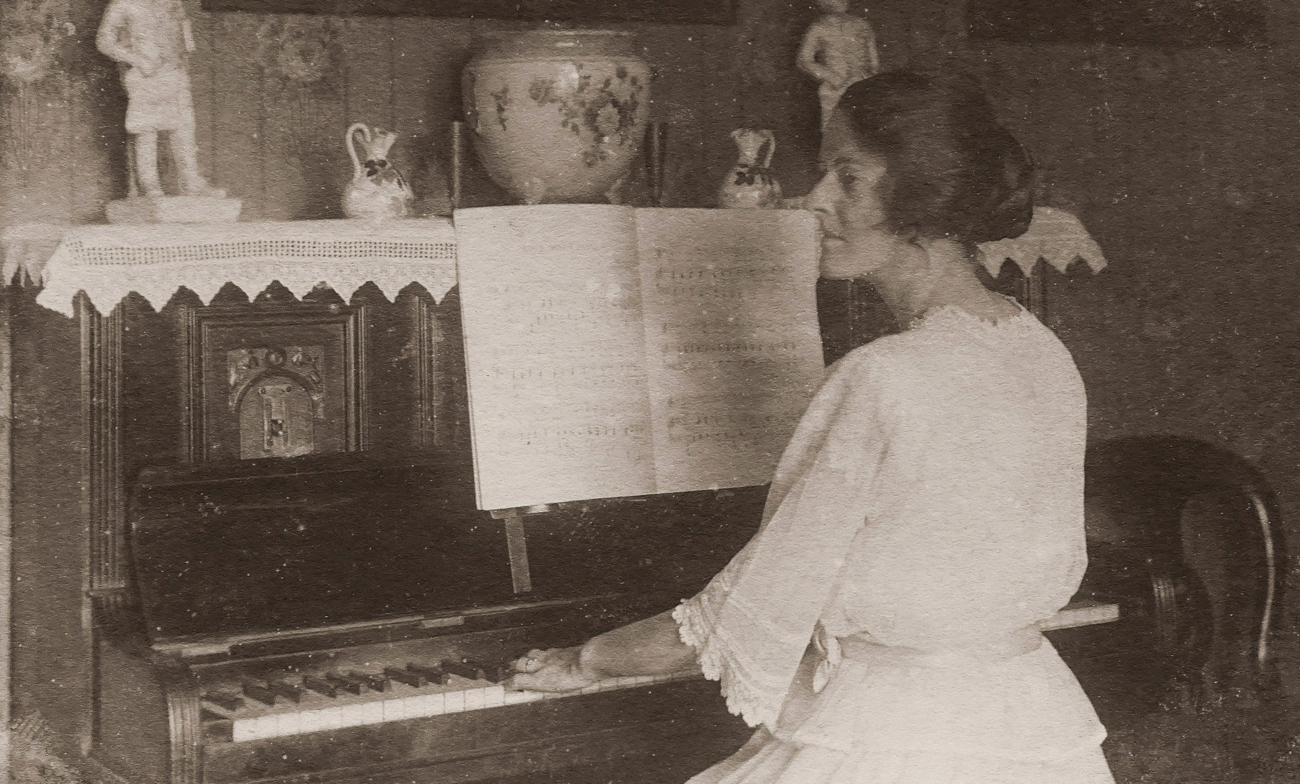 old photo of a lady playing upright piano