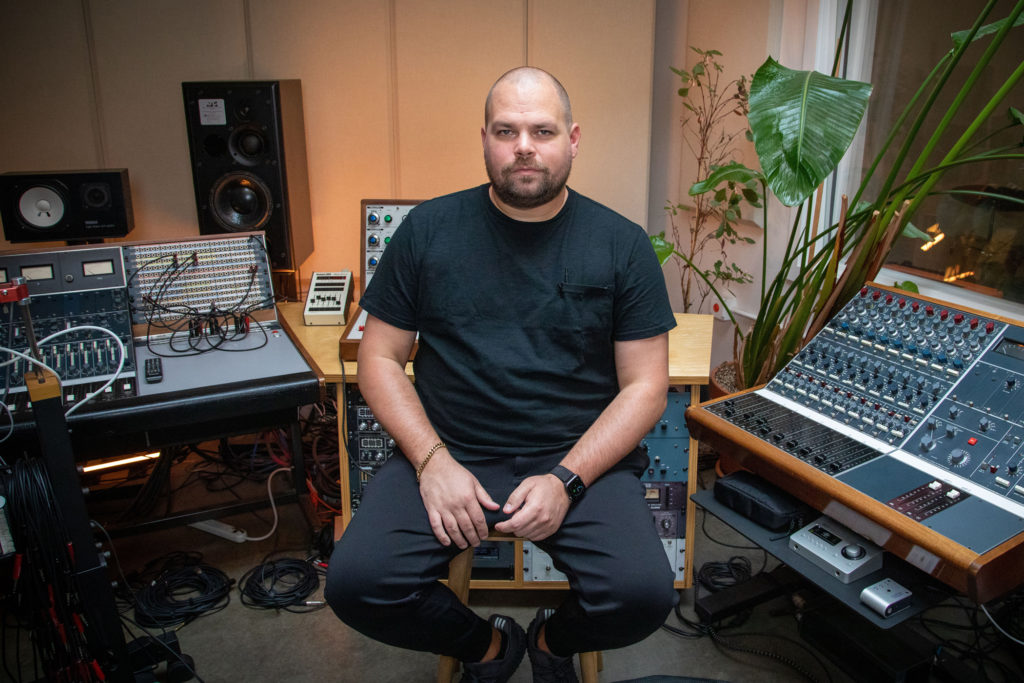 Com Truise in the studio surrounded by gear