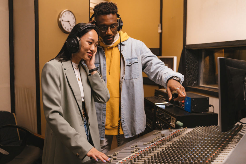 two young people talking at a mixing desk