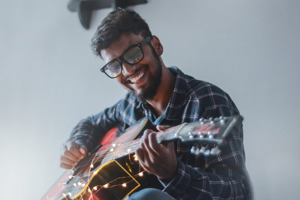 man playing guitar with string lights on it